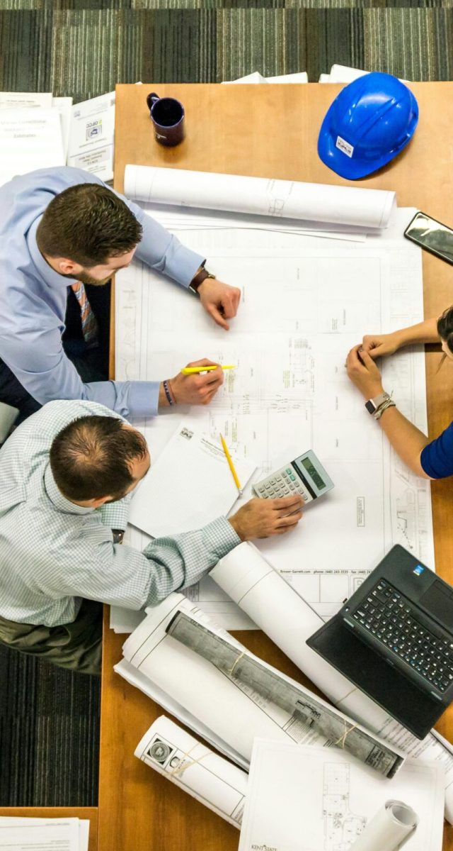 Top view of a team working on construction plans in an office setting.